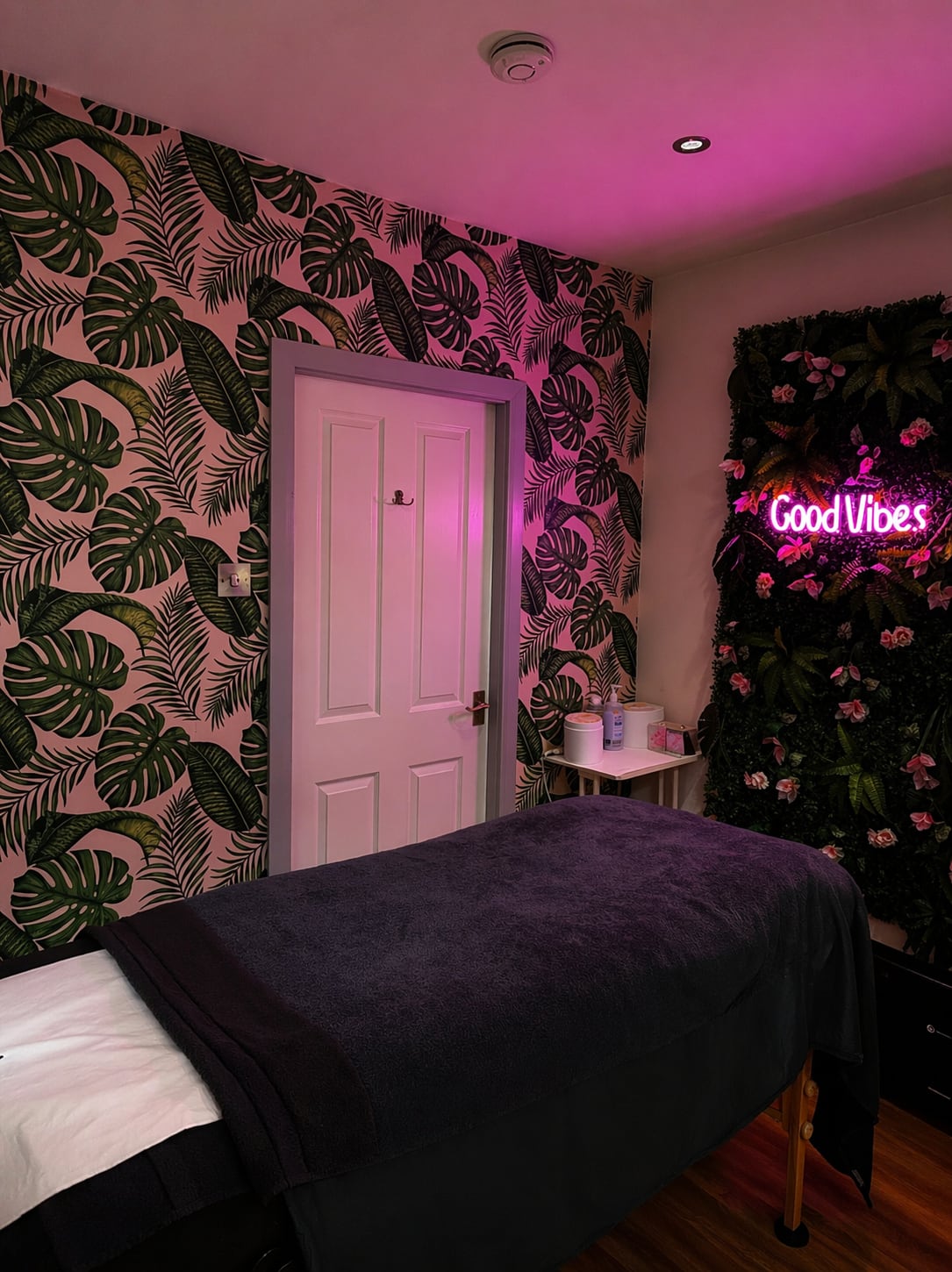 Botanical wallpaper and a softly lit treatment bed at the salon